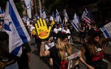 Des personnes brandissant des drapeaux israéliens et des pancartes avant le défilé annuel de la Journée d'Israël, à New York, le 2 juin 2024. (Crédit : Yuki Iwamura/AP)