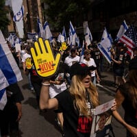 Des personnes brandissant des drapeaux israéliens et des pancartes avant le défilé annuel de la Journée d'Israël, à New York, le 2 juin 2024. (Crédit : Yuki Iwamura/AP)