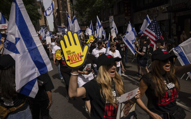 Des personnes brandissant des drapeaux israéliens et des pancartes avant le défilé annuel de la Journée d'Israël, à New York, le 2 juin 2024. (Crédit : Yuki Iwamura/AP)