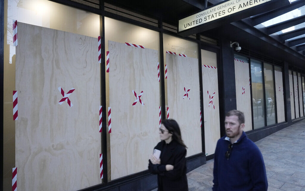 Un couple passe devant les fenêtres remplacées du consulat américain alors que la police enquête sur un acte de vandalisme propalestinien présumé à Sydney, en Australie, le 10 juin 2024. (Crédit : AP Photo/Rick Rycroft)