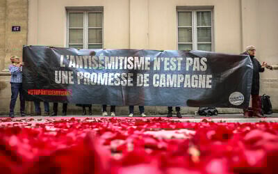Illustration : Des manifestants hissant une banderole sur laquelle on peut lire "L'antisémitisme n'est pas une promesse de campagne" à l'entrée d'une conférence de presse au cours de laquelle les dirigeants français de gauche ont annoncé qu'ils formaient une alliance appelée le nouveau Front populaire, à Paris, en France, le 14 juin 2024. (Crédit : Thomas Padilla/AP)