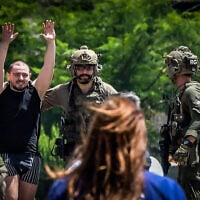 L'otage secouru Almog Meïr Jan levant les mains en signe de joie alors qu'il est escorté depuis un hélicoptère militaire vers l'hôpital Sheba de Ramat Gan, le 8 juin 2024. (Crédit : Avshalom Sassoni/Flash90)