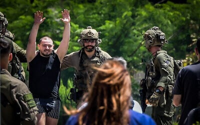 L'otage secouru Almog Meïr Jan levant les mains en signe de joie alors qu'il est escorté depuis un hélicoptère militaire vers l'hôpital Sheba de Ramat Gan, le 8 juin 2024. (Crédit : Avshalom Sassoni/Flash90)