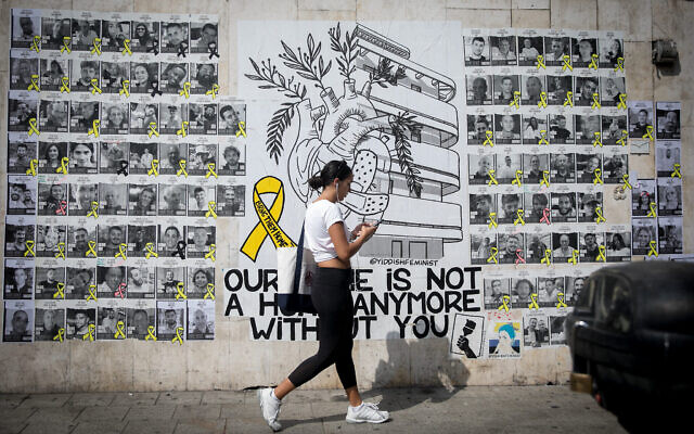 Une femme marchant devant des photographies des otages détenus par les terroristes du Hamas à Gaza depuis le 7 octobre, le 23 juin 2024. (Crédit : Miriam Alster/FLASH90)