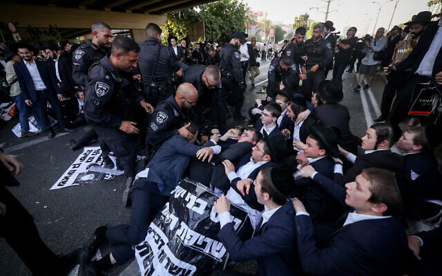Des Juifs ultra-orthodoxes affrontent la police lors d’une manifestation contre l’enrôlement des Haredim dans l’armée, sur la route 4 à l’extérieur de Bnei Brak, le 27 juin 2024. (Crédit : Yonatan Sindel/Flash90)