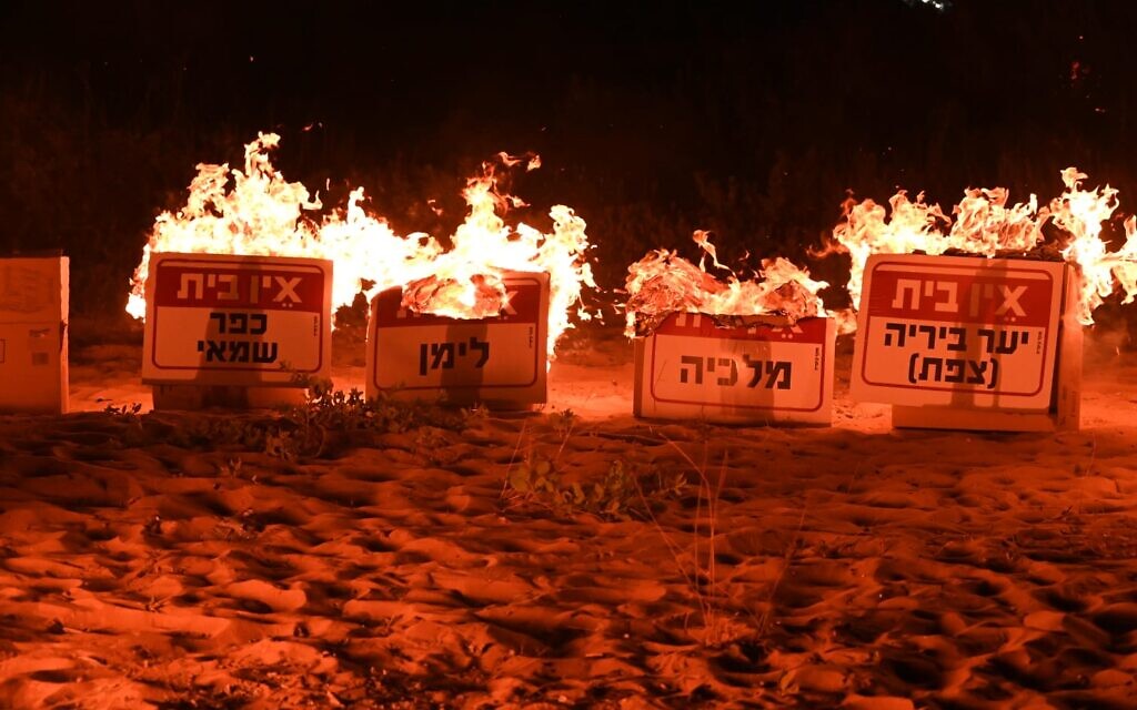 Des manifestants brûlant des pancartes portant les noms de villes du nord d'Israël ravagées par les attaques du Hezbollah et les mots "il n'y a pas de maison" devant le domicile privé du Premier ministre Benjamin Netanyahu, à Caesarea. (Crédit : Alon Banki/Mouvement de protestation pour la démocratie)