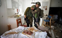 Des soldats de l'unité Lotar pleurant à la vue de la maison du kibboutz Kfar Aza qui avait encore le challah du repas familial de Shabbat de la veille sur la table lorsqu'elle a été attaquée par des terroristes du Hamas le 7 octobre,  le 10 octobre 2023. (Crédit : Ziv Koren/Polaris)