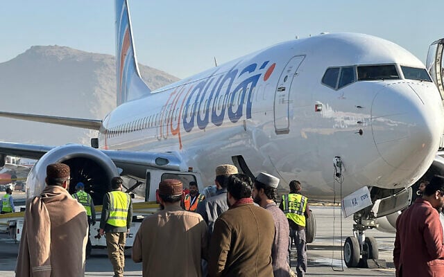 Des personnes se tiennent sur le tarmac à côté d'un avion de la compagnie Flydubai après son atterrissage à l'aéroport international de Kaboul, le 15 novembre 2023. Illustration (Crédit : AFP) Des personnes se tiennent sur le tarmac à côté d'un avion de la compagnie Flydubai après son atterrissage à l'aéroport international de Kaboul, le 15 novembre 2023. Illustration (Crédit : AFP)