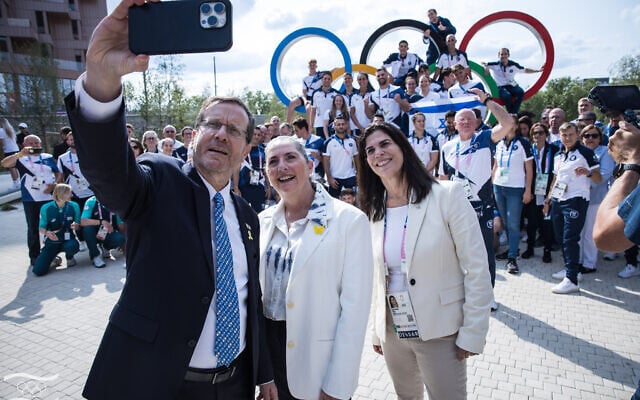 Le président Isaac Herzog, son épouse Michal et la chef du Comité olympique israélien, Yaël Arad, prenant un selfie avec des athlètes israéliens, au village olympique de Paris, le 24 juillet 2024. (Crédit : Oded Karni/Comité olympique israélien)