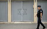 Un policier français montant la garde devant une synagogue, deux jours après que les mesures de sécurité ont été renforcées près des synagogues et des écoles juives, dans le centre de Paris, le 9 octobre 2023. (Crédit : Julien de Rosa/AFP)