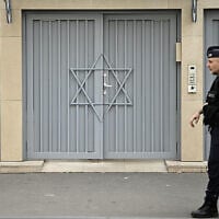 Un policier français montant la garde devant une synagogue, deux jours après que les mesures de sécurité ont été renforcées près des synagogues et des écoles juives, dans le centre de Paris, le 9 octobre 2023. (Crédit : Julien de Rosa/AFP)