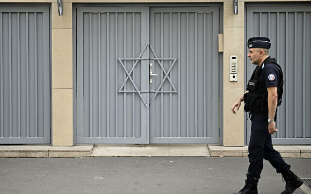 Un policier français montant la garde devant une synagogue, deux jours après que les mesures de sécurité ont été renforcées près des synagogues et des écoles juives, dans le centre de Paris, le 9 octobre 2023. (Crédit : Julien de Rosa/AFP)