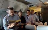 Des responsables, des journalistes et des proches d'otages prient dans l'avion officiel "Aile de Sion" du Premier ministre Benjamin Netanyahu en partance pour Washington, DC, le 22 juillet 2024. (Crédit : Pool)
