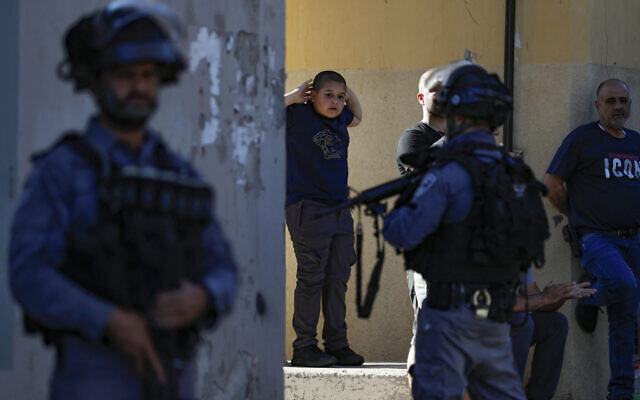 Un jeune garçon regardant les forces de sécurité israéliennes se rassembler lors d'une manifestation, à Jaffa, le 15 mai 2021. (Crédit : Ahmad Gharabli/AFP)