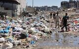 Des Palestiniens parmi des monticules d'ordures et des égouts à ciel ouvert, dans le quartier de Sheikh Radwan, au nord de la ville de Gaza, le 3 juillet 2024. (Crédit : Omar al-Qattaa/AFP)