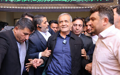 Le candidat réformiste à la présidence iranienne Masoud Pezeshkian (au centre) quittant un bureau de vote après avoir voté, à Téhéran le 5 juillet 2024 (Crédit : Atta Kenare/AFP) 