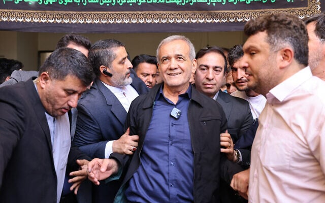 Le candidat réformiste à la présidence iranienne Masoud Pezeshkian (au centre) quittant un bureau de vote après avoir voté, à Téhéran le 5 juillet 2024 (Crédit : Atta Kenare/AFP) 