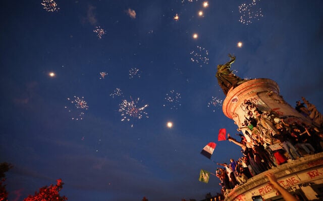 Des gens brandissent les drapeaux tricolores français alors que des feux d'artifice illuminent le ciel lors d'un rassemblement nocturne après les premiers résultats du deuxième tour des élections législatives françaises, place de la République à Paris, le 7 juillet 2024. (Crédit : Emmanuel Dunand/AFP) Des gens brandissent les drapeaux tricolores français alors que des feux d'artifice illuminent le ciel lors d'un rassemblement nocturne après les premiers résultats du deuxième tour des élections législatives françaises, place de la République à Paris, le 7 juillet 2024. (Crédit : Emmanuel Dunand/AFP)
