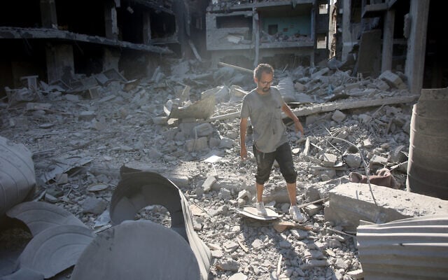 Un Palestinien marchant sur les décombres de bâtiments détruits après le retrait de l'armée israélienne du quartier de Shejaiya, à l'est de Gaza City, le 10 juillet 2024. (Crédit : Omar al-Qattaa/AFP) Un Palestinien marchant sur les décombres de bâtiments détruits après le retrait de l'armée israélienne du quartier de Shejaiya, à l'est de Gaza City, le 10 juillet 2024. (Crédit : Omar al-Qattaa/AFP)