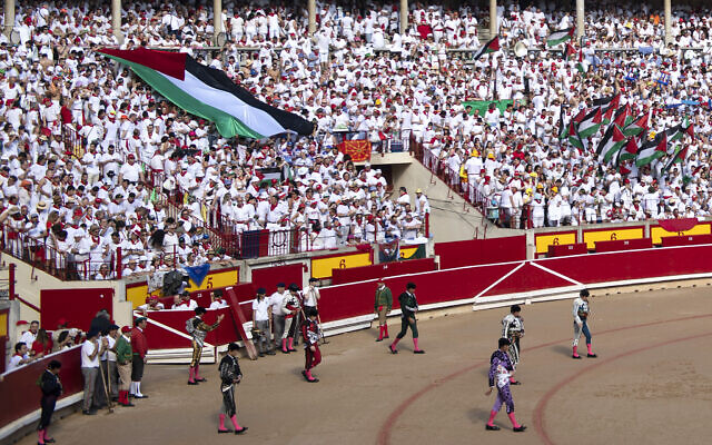 Des membres de "Las Penas" (associations culturelles et festives) déployant un drapeau palestinien sur la section soleil des arènes au début de la cinquième corrida du festival de San Fermin, à Pampelune, dans le nord de l'Espagne, le 11 juillet 2024. (Crédit : Ander Gillenea/AFP)