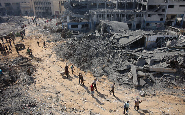 Des personnes marchant sur les décombres du complexe immobilier endommagé de l'Office controversé de secours et de travaux des Nations unies pour les réfugiés de Palestine dans le Proche-Orient (UNRWA) dans le quartier Al-Sinaa de la ville de Gaza, le 12 juillet 2024, après le retrait des troupes israéliennes de la zone. (Crédit : Omar Al-Qattaa/AFP) Des personnes marchant sur les décombres du complexe immobilier endommagé de l'Office controversé de secours et de travaux des Nations unies pour les réfugiés de Palestine dans le Proche-Orient (UNRWA) dans le quartier Al-Sinaa de la ville de Gaza, le 12 juillet 2024, après le retrait des troupes israéliennes de la zone. (Crédit : Omar Al-Qattaa/AFP)