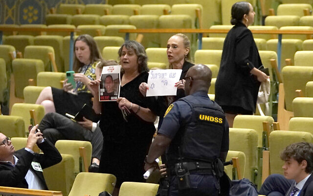 Des manifestants brandissent une photo d'un otage israélien et un panneau pendant une rencontre du Conseil de sécurité consacrée à la situation au Moyen-Orient, le 17 juillet 2024. (Crédit : Timothy A. Clary/AFP) Des manifestants brandissent une photo d'un otage israélien et un panneau pendant une rencontre du Conseil de sécurité consacrée à la situation au Moyen-Orient, le 17 juillet 2024. (Crédit : Timothy A. Clary/AFP)