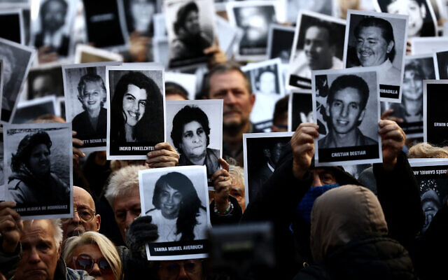 Des personnes tenant des photos de victimes lors d'une cérémonie commémorant l'anniversaire de l'attentat de l'Association mutuelle israélite d'Argentine (AMIA), à Buenos Aires, le 18 juillet 2024. (Crédit : Tomas Cuesta/AFP)