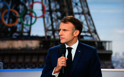 Le président français Emmanuel Macron lors d'une interview en direct sur la chaîne de télévision française France 2, sur un plateau installé sur le toit du Musée de l'Homme au Trocadéro, avec les anneaux des Jeux olympiques en arrière-plan, à Paris, le 23 juillet 2024.  (Crédit : Ludovic Marin/AFP)