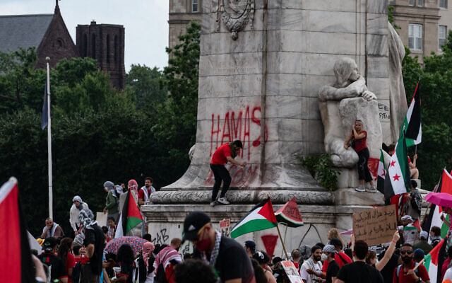 Une personne taggant à la bombe sur la base de la fontaine commémorative de Christophe Colomb alors que des manifestants pro-palestiniens protestent près du Capitole des États-Unis alors que le Premier ministre Benjamin Netanyahu s'adresse à une réunion conjointe du Congrès, à Washington, le 24 juillet 2024. (Crédit : Andrew Thomas/AFP) Une personne taggant à la bombe sur la base de la fontaine commémorative de Christophe Colomb alors que des manifestants pro-palestiniens protestent près du Capitole des États-Unis alors que le Premier ministre Benjamin Netanyahu s'adresse à une réunion conjointe du Congrès, à Washington, le 24 juillet 2024. (Crédit : Andrew Thomas/AFP)