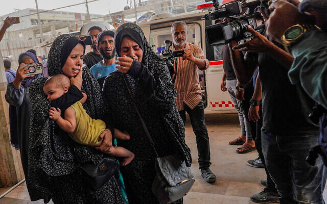Des curieux et des journalistes filmant devant l'hôpital Nasser où les blessés arrivent après un bombardement à Khan Younès, dans le sud de la bande de Gaza, le 25 juillet 2024. (Crédit : Bashar Taleb/AFP)
