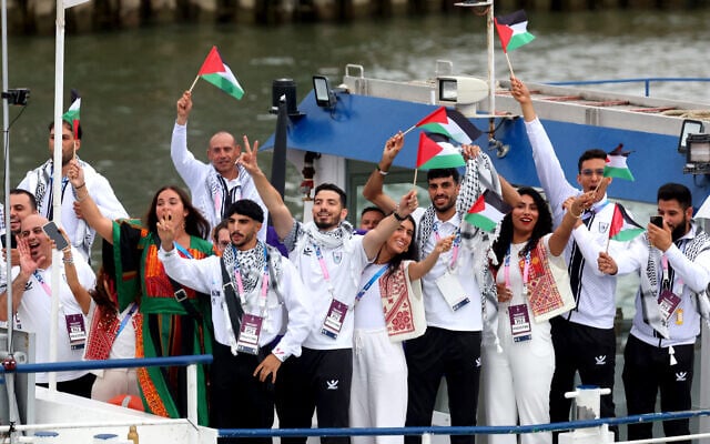 Les athlètes de la délégation palestinienne agitent des drapeaux sur le bateau de l'équipe du défilé des athlètes le long de la Seine lors de la cérémonie d'ouverture des Jeux olympiques Paris 2024, le 26 juillet 2024 (Photo by Michael Reaves / POOL / AFP)