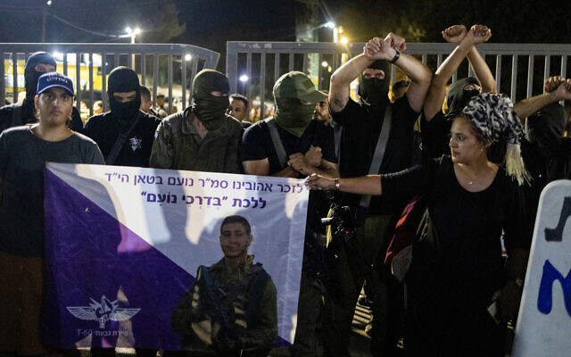 Des manifestants israéliens de droite, dont certains portent des uniformes militaires et des armes, se rassemblent devant la base militaire de Bayt Lid pour protester contre la détention pour interrogatoire de réservistes soupçonnés d'avoir maltraité un terroriste interpellé à la suite de l'attaque du 7 octobre en Israël, le 29 juillet 2024 à Kfar Yona. (Crédit : Oren Ziv / AFP)