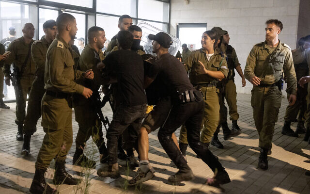Des soldats et des policiers israéliens affrontant des manifestants d'extrême droite qui ont pénétré dans la base militaire de Beit Lid, à Kfar Yona, le 29 juillet 2024. (Crédit : Oren Ziv/AFP)