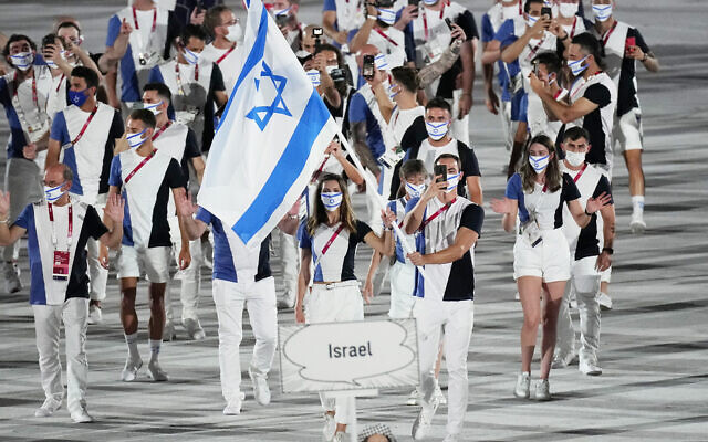 Les sportifs israéliens Hanna Minenko et Yakov Toumarkin portant le drapeau national lors de la cérémonie d'ouverture, dans le stade olympique des Jeux olympiques d'été de 2020, à Tokyo, au Japon, le 23 juillet 2021. (Crédit : David J. Phillip/AP) Les sportifs israéliens Hanna Minenko et Yakov Toumarkin portant le drapeau national lors de la cérémonie d'ouverture, dans le stade olympique des Jeux olympiques d'été de 2020, à Tokyo, au Japon, le 23 juillet 2021. (Crédit : David J. Phillip/AP)