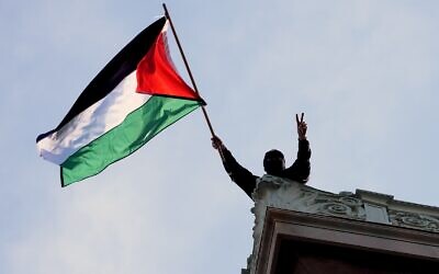 Un étudiant manifestant agitant un drapeau palestinien au-dessus du Hamilton Hall, sur le campus de l'Université Columbia, à New York, le 30 avril 2024. (Crédit : Mary Altaffer/AP/Pool)