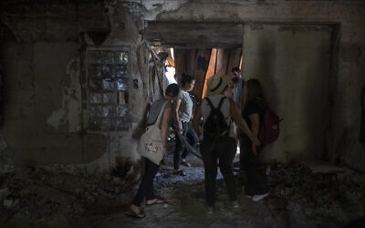 Un groupe d'Israéliens visite une maison incendiée par les terroristes du Hamas pendant le pogrom lancé par le groupe en Israël au kibboutz Nir Oz, le 21 juin 2024. (Crédit : AP Photo/Ohad Zwigenberg)