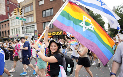 Une femme brandit un drapeau des Fiertés arc-en-ciel avec l'étoile de David pendant la Gay Pride de New York City, le 30 juin 2024. (Crédit : A Charles Sykes/Invision/AP) Une femme brandit un drapeau des Fiertés arc-en-ciel avec l'étoile de David pendant la Gay Pride de New York City, le 30 juin 2024. (Crédit : A Charles Sykes/Invision/AP)