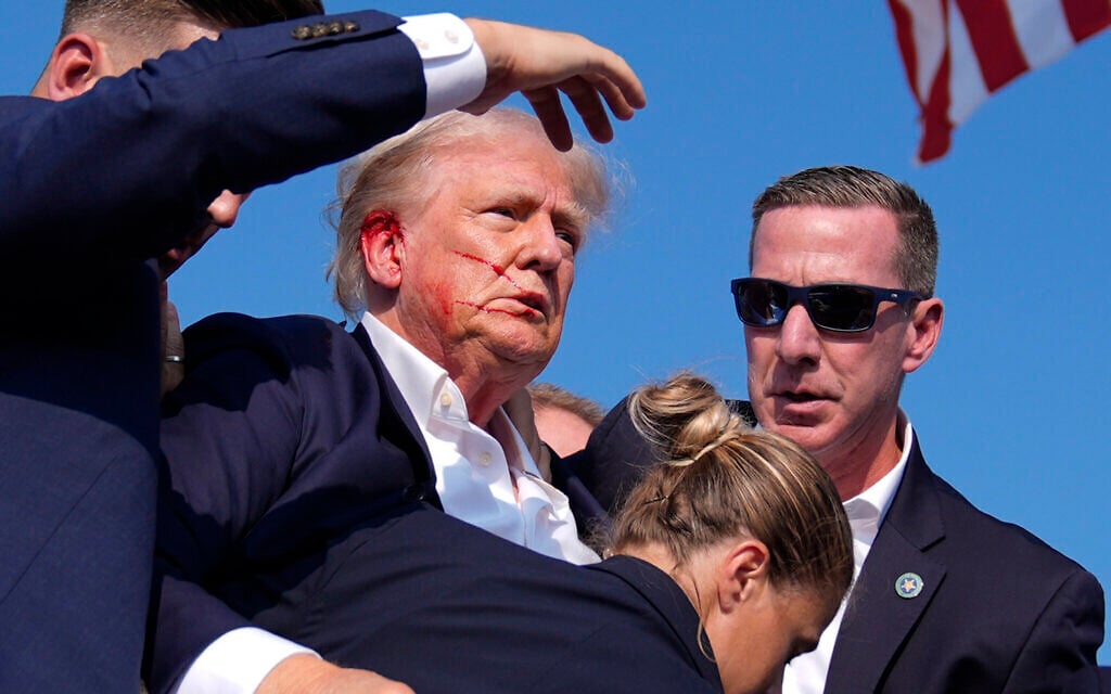 Le candidat à la présidence américaine, l'ancien président Donald Trump, entouré par des agents secrets américains alors qu'il quitte la scène d'un rassemblement de campagne à Butler, en Pennsylvanie, le 13 juillet 2024. (Crédit : AP Photo/Evan Vucci)