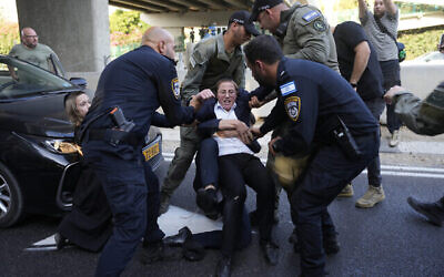 La police évacue des jeunes juifs ultra-orthodoxes qui bloquent une route pour protester contre le recrutement militaire à Bnei Brak, près de Tel Aviv, en Israël, le mardi 16 juillet 2024. (Crédit  : AP Photo/Ohad Zwigenberg)