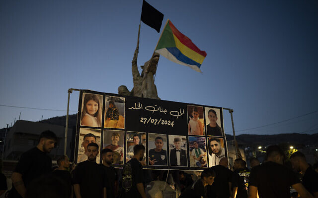 Les photos des enfants et des adolescents tués par un tir de roquette sur un terrain de football sont affichées sur un rond-point en leur mémoire, dans le village de Majdal Shams, sur le plateau du Golan, le dimanche 28 juillet 2024. (Crédit : AP/Leo Correa)