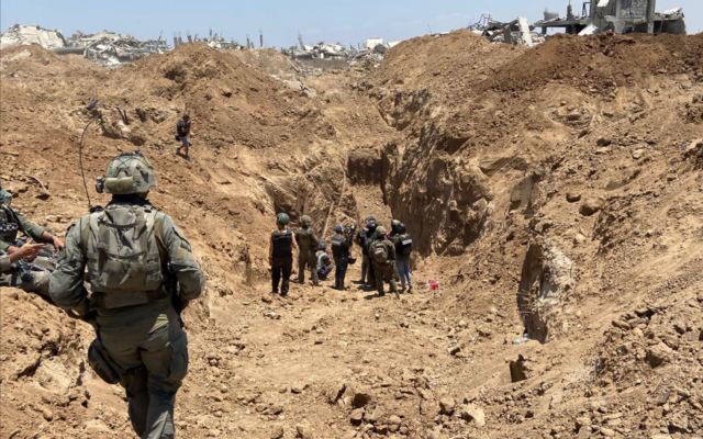 Des soldats israéliens se dirigent vers l'entrée d'un tunnel qui a été découvert dans le quartier de Shejaiya de Gaza City, le 8 juillet 2024. (Crédit : David Horovitz / Times of Israel)