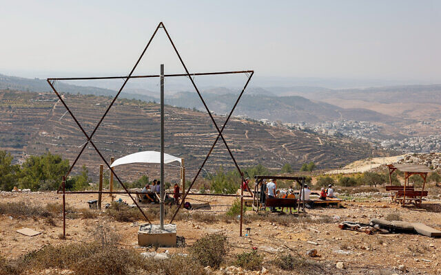 Des Israéliens célébrant la fête de Souccot devant une grande étoile de David, dans l'implantation de Sde Boaz, dans le Gush Etzion, le 11 octobre 2022. (Crédit : Gershon Elinson/Flash90)