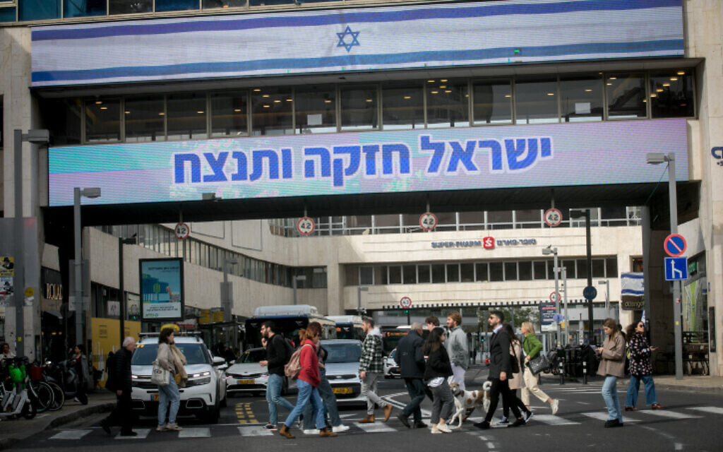 Des Israéliens passant devant un grand panneau d'affichage indiquant « Israël est fort et gagnera », sur la rue Dizengoff, à Tel Aviv, le 17 janvier 2024. (Crédit : Miriam Alster/FLASH90) Des Israéliens passant devant un grand panneau d'affichage indiquant « Israël est fort et gagnera », sur la rue Dizengoff, à Tel Aviv, le 17 janvier 2024. (Crédit : Miriam Alster/FLASH90)