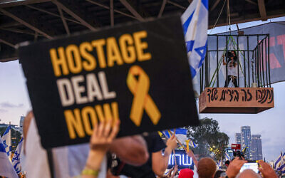 Des manifestants protestant pour la libération des otages dans la bande de Gaza, devant les quartiers généraux de l'armée de la Kirya, à Tel Aviv, le 7 juillet 2024. Einav Zangauker, la mère de l'otage Matan Zangauker, se tenant dans la cage à gauche avec l'inscription " Netanyahu, c'est entre vos mains". (Crédit : Itaï Ron/Flash90)