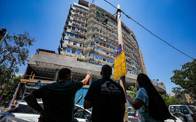 Des personnes regardant un bâtiment touché par un drone lors de l'attaque meurtrière du 18 juin, à Tel Aviv, le 19 juillet 2024. (Crédit : Jamal Awad/Flash90)