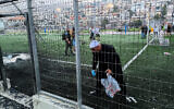 Les secouristes israéliens et les locaux sur le site d'une attaque à la roquette du Hezbollah sur un terrain de football dans la ville de Majdal Shams, au nord du Golan, le 27 juillet 2024. (Crédit : Michael Giladi/Flash90)