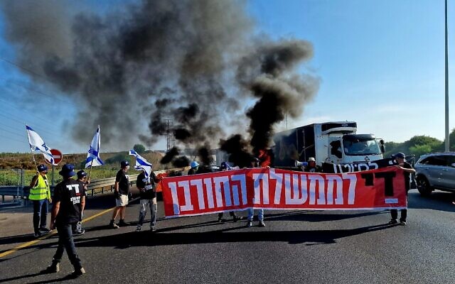 Des manifestants anti-gouvernement brandissant une banderole sur laquelle on peut lire "Assez du gouvernement de destruction", à la jonction de Morasha, dans le centre d'Israël, le 10 juillet 2024. (Crédit : Danor Aharon/Mouvement de protestation pour la démocratie)