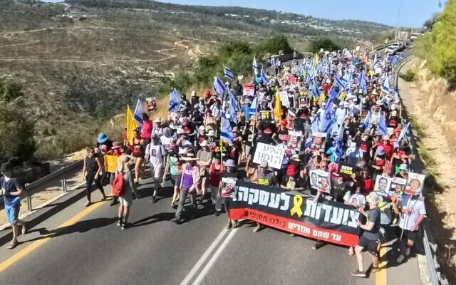 Des militants pour les otages de Gaza participant à une marche vers Jérusalem avec des fumigènes jaunes pour attirer l'attention sur le sort des personnes enlevées par le Hamas, à proximité de Shoresh, le 12 juillet 2024. (Crédit : sha_b_p@/ Mouvement de protestation pour la démocratie)