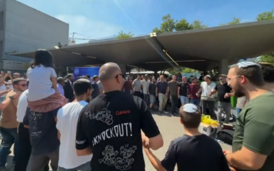 Des jeunes hommes qui s’apprêtent à rejoindre les rangs de l’armée, dont des étudiants de yeshivot ultra-orthodoxes, dansent et chantent ensemble au centre de conscription de Tsahal à Tel Aviv, le 7 août 2024 (Crédit : Capture d’écran/X)