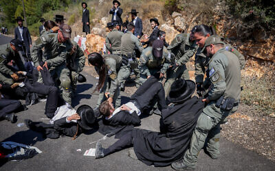 Des Juifs ultra-orthodoxes se heurtant à la police lors d'une manifestation contre l'enrôlement des Haredim étudiant en yeshiva dans l’armée israélienne, devant la base militaire de Mihve Alon, dans le nord d'Israël, le 14 août 2024. (Crédit : David Cohen/Flash90)